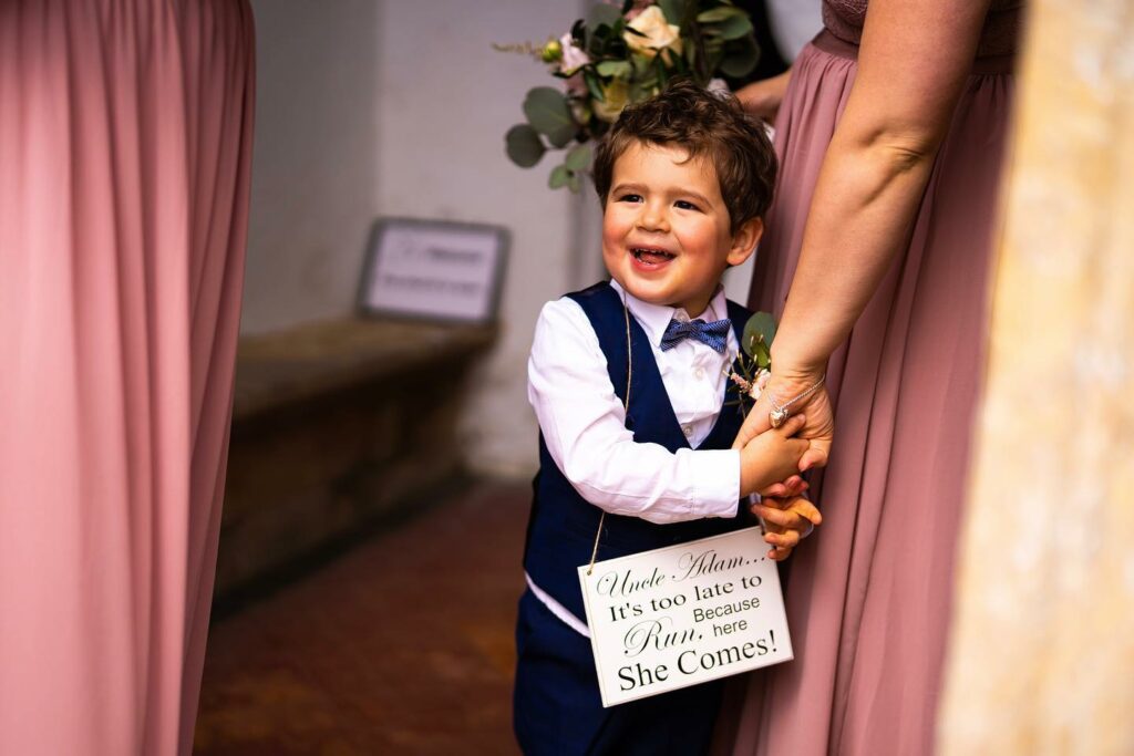 page boy holding a wedding sign about to walk down the aisle